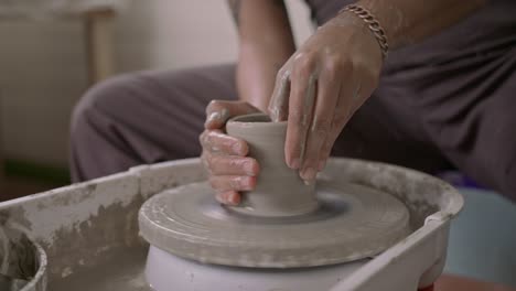 close-up of hands shaping clay on a pottery wheel with focus and precision, indoors, during the day