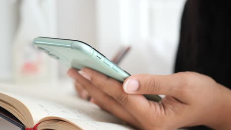 woman writing in a notebook while holding a phone