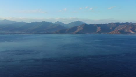 high mountains of volcanic islands in indonesia surrounded by deep blue sea, clear bright blue sky