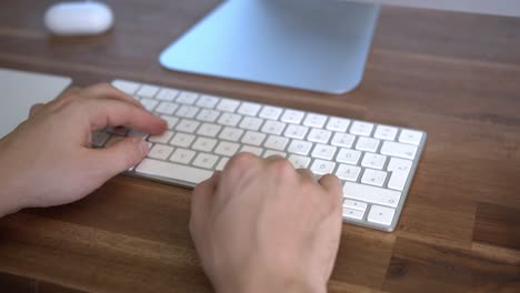 manos escribiendo en el teclado de la computadora sentado en el escritorio de la oficina en casa