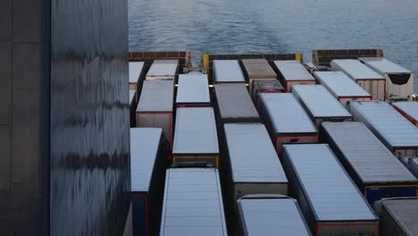 the semi-trailers, together with the truks, are parked on the open deck of the ferry when it is currently sailing in the sea