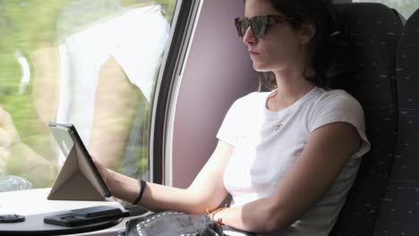 Young-woman-using-tablet-ebook-on-train-journey