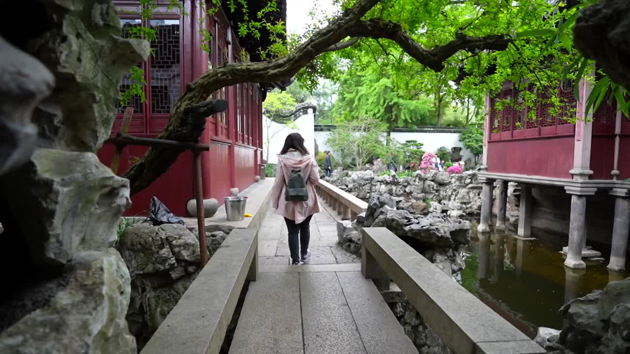 POV following a tourist who stops to photograph a pagoda at Yuyuan Garden in Shanghai, China