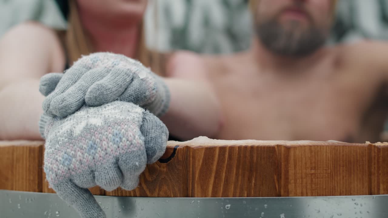 Close up of woman's hands in gloves during the winter bath with man in forest