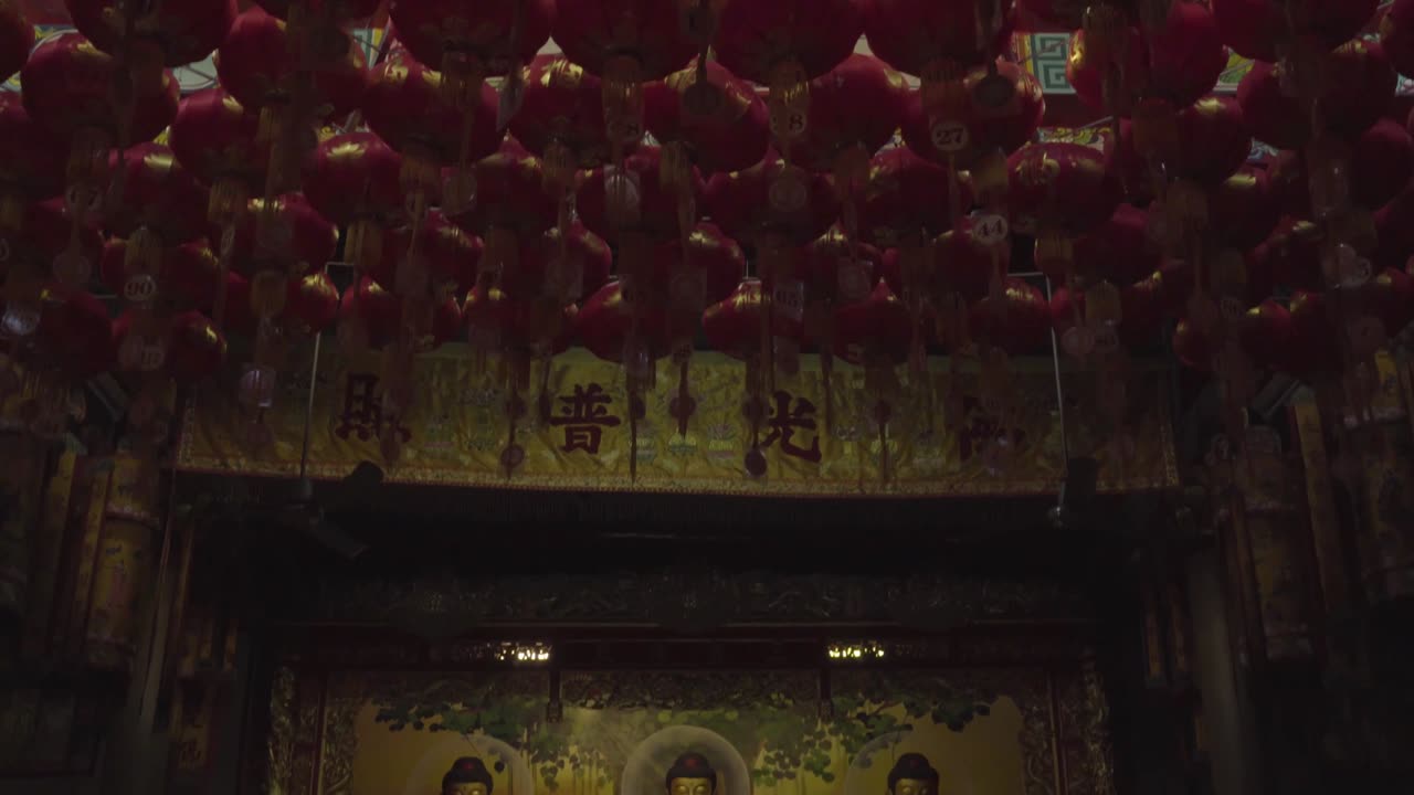 Red lanterns on ceiling with Yin Yang symbol in the middle, buddha statues