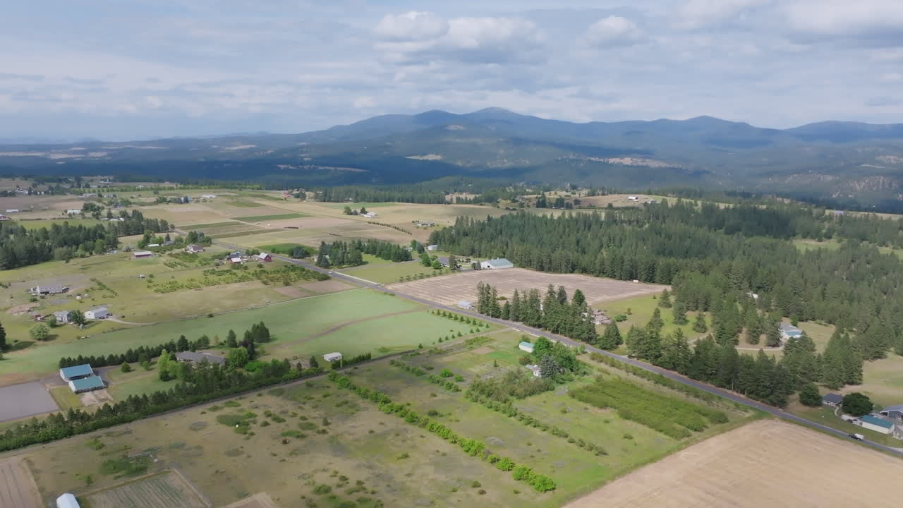 Aerial video of sprawling farmland and orchards with mountains on the horizon near Spokane, Washington