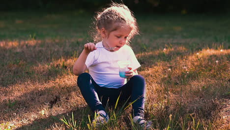 young lady eats yogurt with metal spoon sitting on meadow