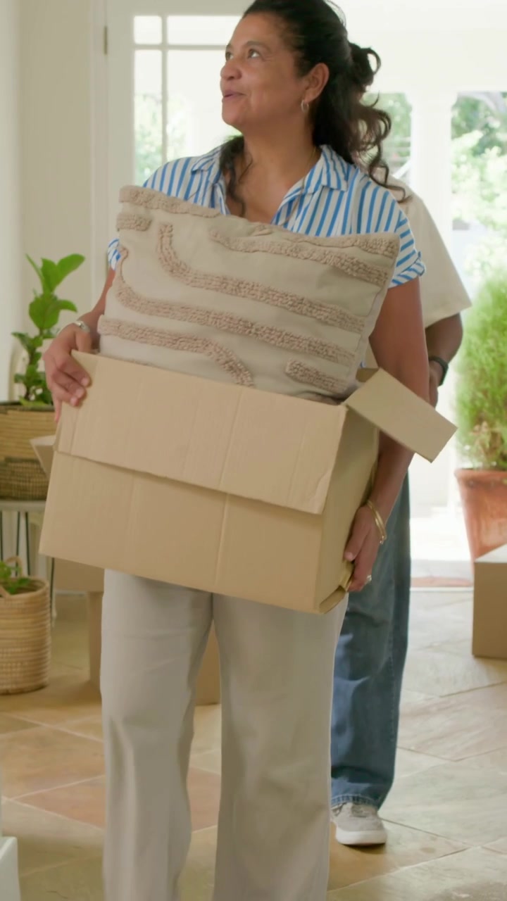 Video vertical: Abriendo la puerta principal, una pareja cargando cajas entra al vestíbulo, desempacando en casa