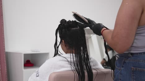 latina teen combed by stylist in salon, professional hydration treatment