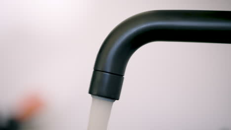 static side close-up of black water faucet being turned on and off