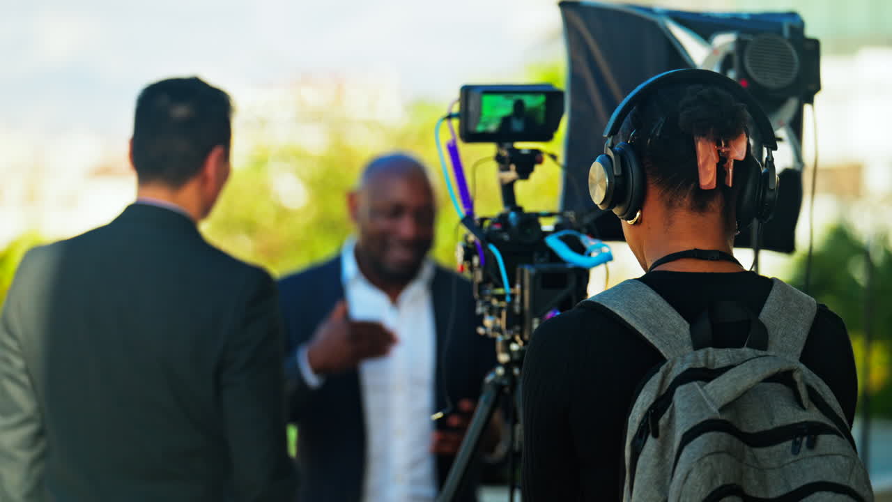 Videographers with professional equipment filming two men talking outside in Cannes, France