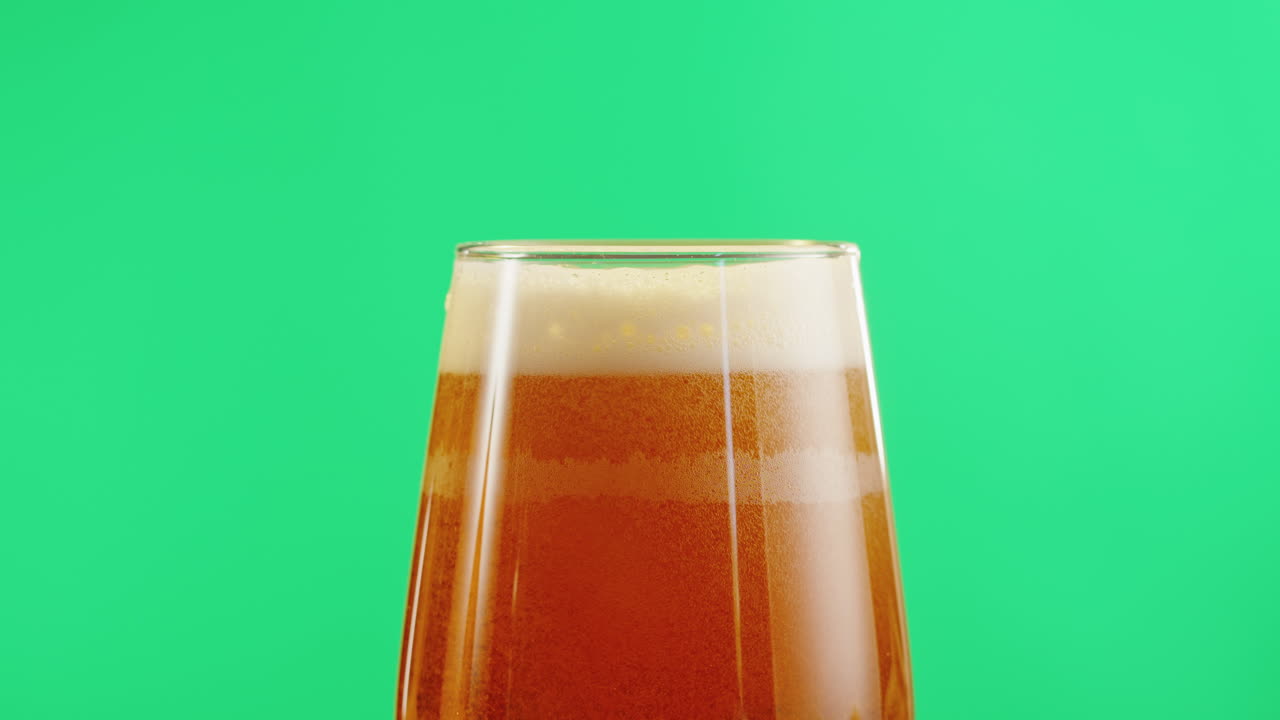 un vaso de cerveza sobre un fondo verde