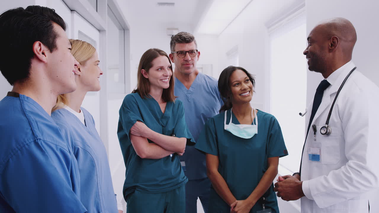Equipe médica multicultural em reunião no corredor do hospital.