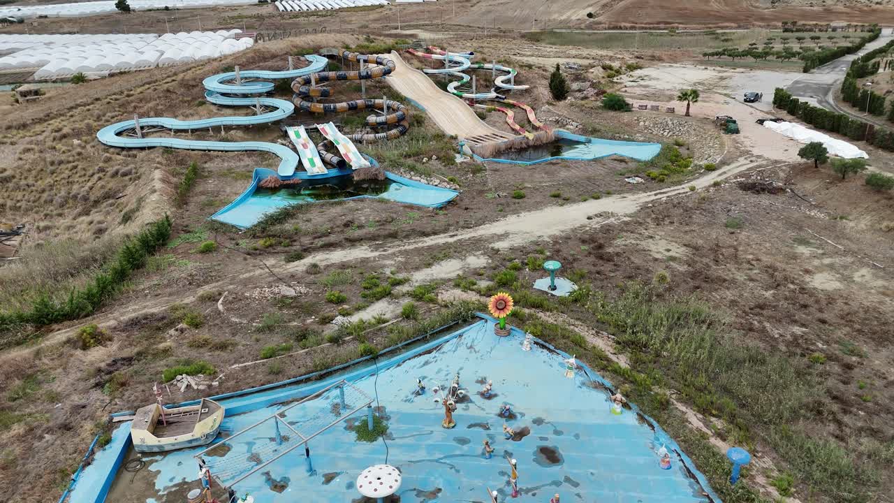 An abandoned children’s splash zone showing empty pools, faded play structures, and neglected water features, followed by the surrounding waterslides of a long-closed park
