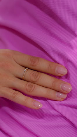 primer plano de manos ayudando a una mujer con ropa deportiva rosa mientras realiza un estiramiento de la columna vertebral, una mano lleva un anillo, y la otra un reloj inteligente, simbolizando la orientación profesional en un entorno de gimnasio