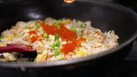 Koch-Streut-Masago-Fischrogen-über-Frisch-Zubereiteten-Gebratenen-Krabbenreis-In-Der-Bratpfanne,-Nahaufnahme-In-Zeitlupe-4k