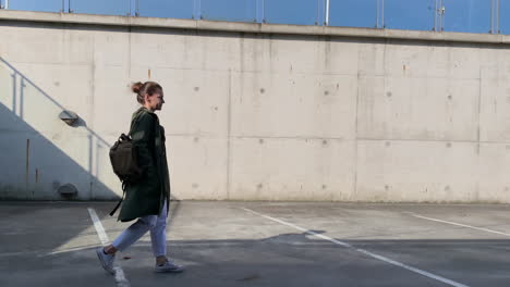 girl walks front of a plain garage wall