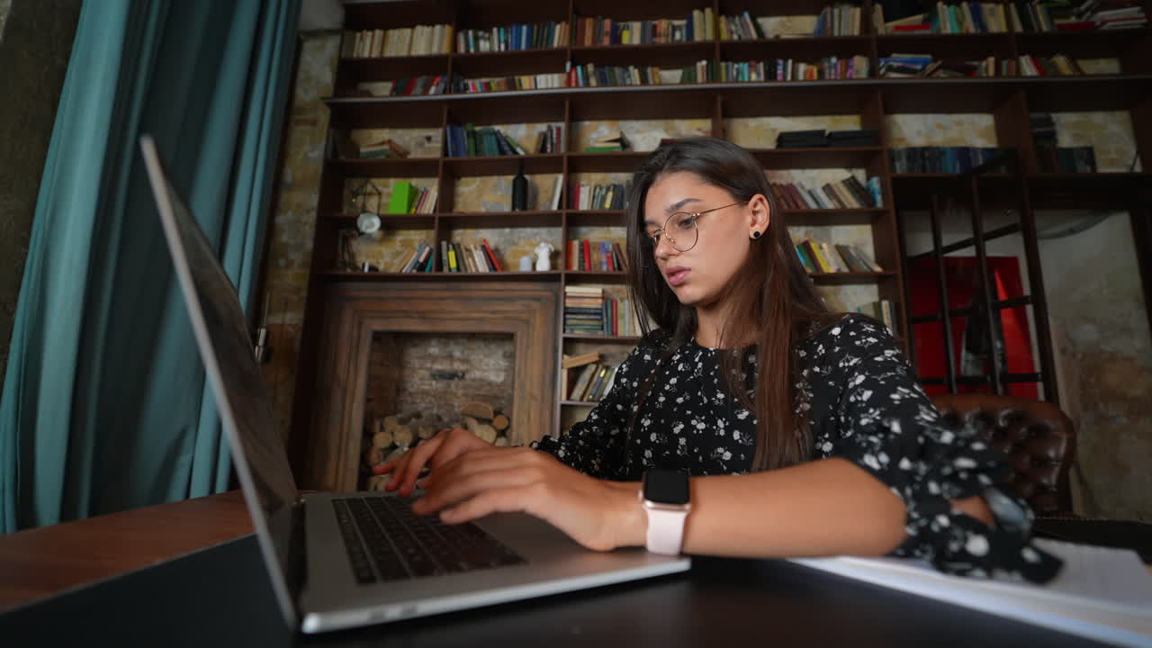 mujer trabajando en una computadora portátil en una biblioteca