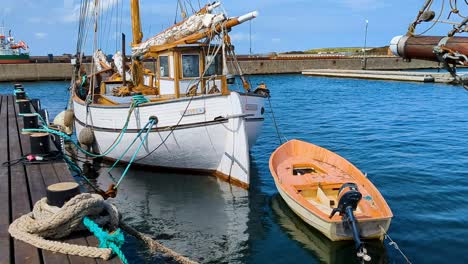 Altes-Weißes-Vintage-Segelschiff-Im-Kleinen-Schwedischen-Hafen-Mit-Einem-Rettungsboot-Und-Einem-Außenbordmotor