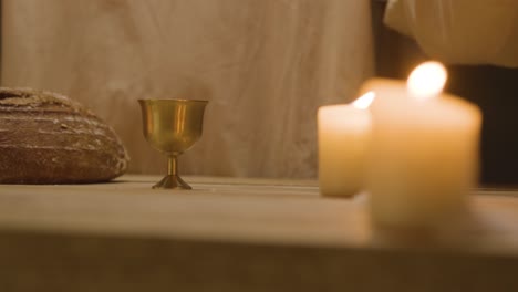 close up shot of man wearing robes representing figure of jesus christ blessing bread and wine