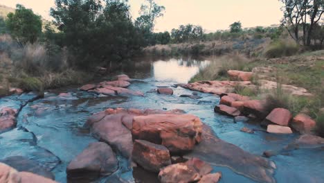 rocky ford over small river in african landscape, backward dolly shot