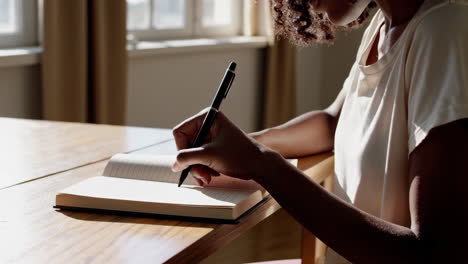 person writing and journaling in a sunlit room