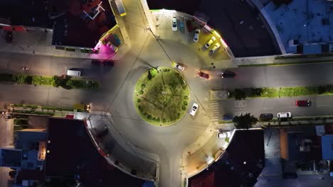 nighttime top-down drone shot of a roundabout with commercial establishments around the perimeter and low vehicle traffic moving east-west in a neighborhood of cuautitlán izcalli, state of mexico