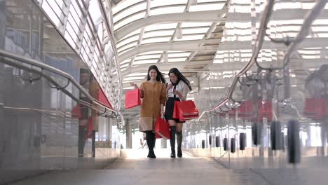 beautiful young woman shopping together in city. lady holding red shopping bag on hands.