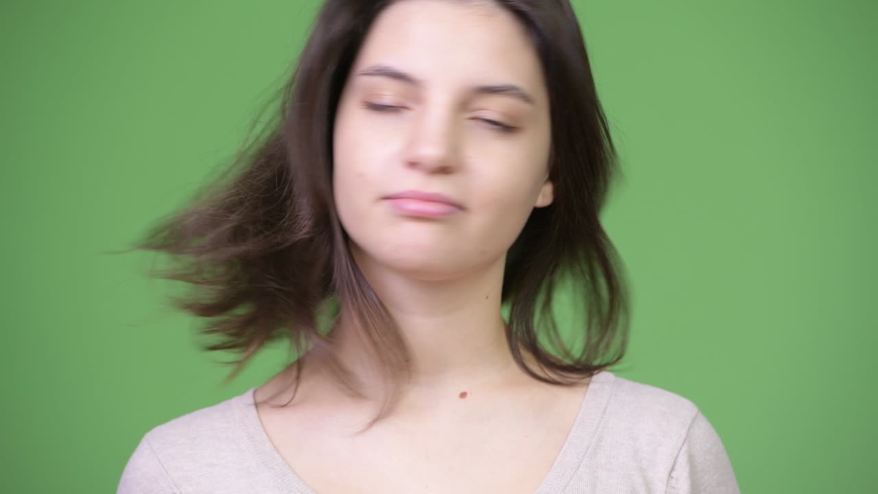 아름다운 젊은 여성이 초록색 배경에 대해 "아니요"라고 고개를 끄덕인다.