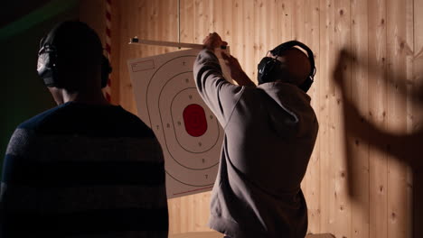 man in firing range doing shooting sport, looking at results on paper target