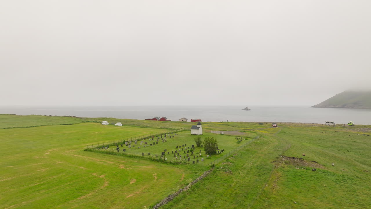 노르웨이 베스트바고야 의 안개 가 가득 한 날 에 언스타드 예배당 과 언스타드 묘지 위 를 날아다니는 새 들 의 항공 사진