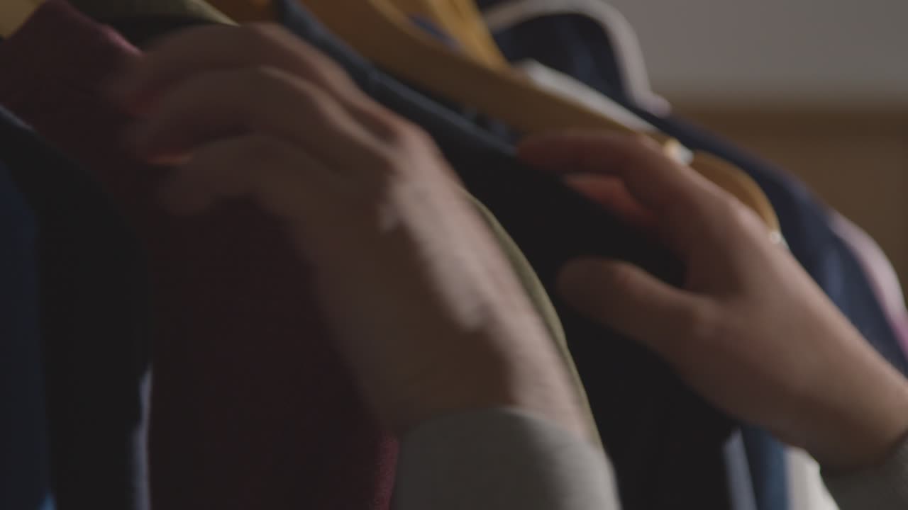 직장 면접을 위해 옷걸이에서 비즈니스 정장을 선택하는 집에 있는 남자의 클로즈업