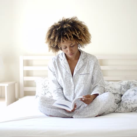 Woman-Reading-A-Book-On-Bed