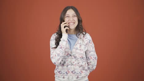 행복한 젊은 여자가 전화로 얘기하고 있습니다.