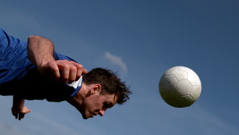 jugador de fútbol encabezando la pelota bajo el cielo azul