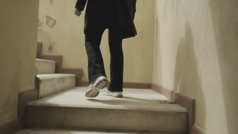 extreme slow motion of a person climbing stairs in dimly lit environment, camera positioned behind