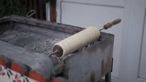 traditional hungarian dessert: kurtoskalacs being cooked on mild fire