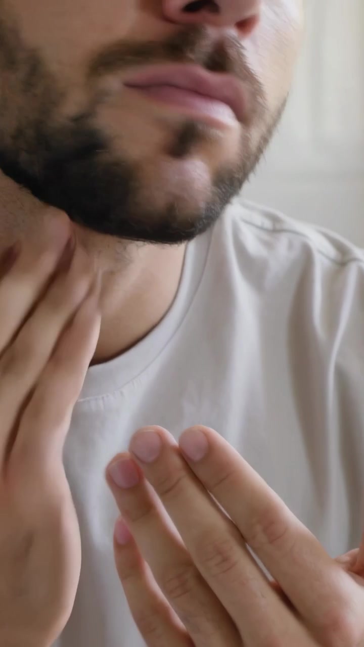 Video verticale: Mani che premono, un uomo adulto che si cura la barba in bagno, indossando una maglietta girocollo.