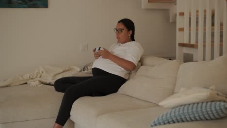 una hermosa mujer embarazada sentada cómodamente en casa, disfrutando de videojuegos en una consola de televisión. la escena mezcla relajación, entretenimiento moderno y maternidad en un entorno acogedor