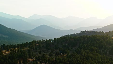 scenic aerial trucking pan over estes park, colorado, autumn colors and sunlight casting across mountains, stunning layers of ridges off into distance, telephoto compression
