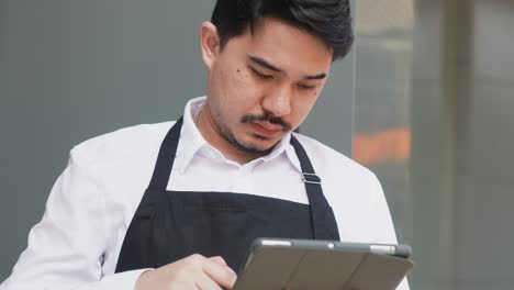 slow motion scene adult middle east businessman owner hold digital tablet to check about inventory or ordering from customer in front of shop for sme business and startup concept