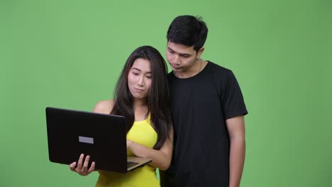 Young happy Asian couple using laptop together