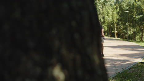 Long-shot-of-man-with-bionic-leg-cycling-along-path-in-park