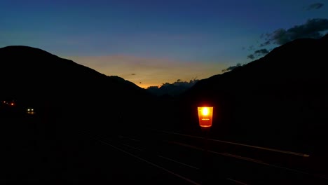 evening scene of mountain road, where single streetlamp glows, twilight sky, drone