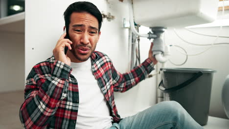 man on phone call repairing a leaky sink