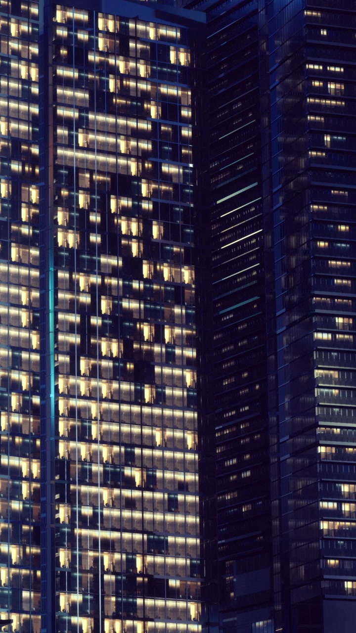 City lights shine from tall buildings at night in urban environment