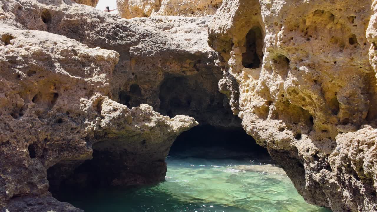 Sunlight reflecting on turquoise water surface inside hidden sea cave in Carvoeiro, Portugal, creating magical atmosphere