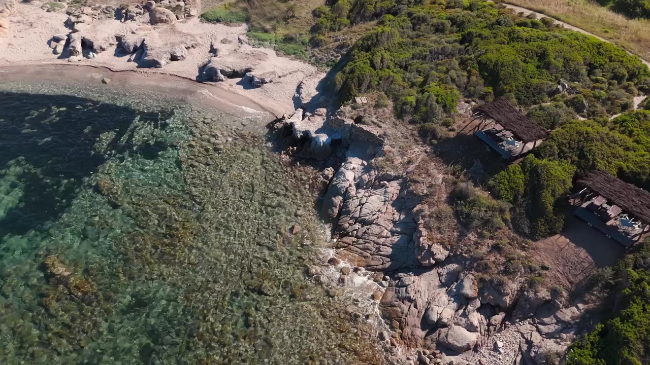 Widok z lotu ptaka na skaliste wybrzeże, czyste morze i rustykalne schronienia przy śródziemnomorskiej plaży