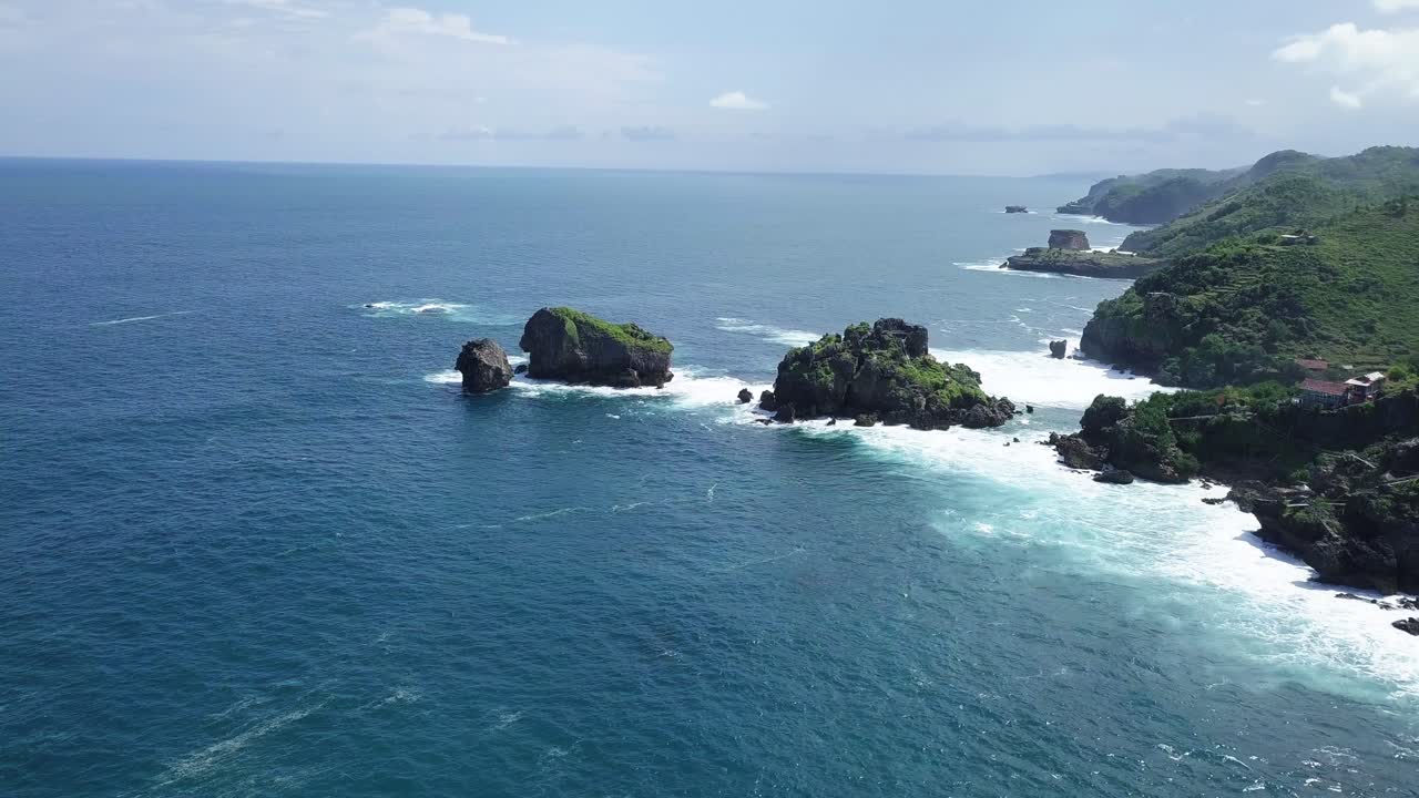 toma de drones de islas rocosas en la playa, golpeadas por olas durante el día soleado - isla timang, yogyakarta, indonesia