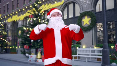 papá noel asiático señalando a sí mismo mientras está de pie en la noche de navidad